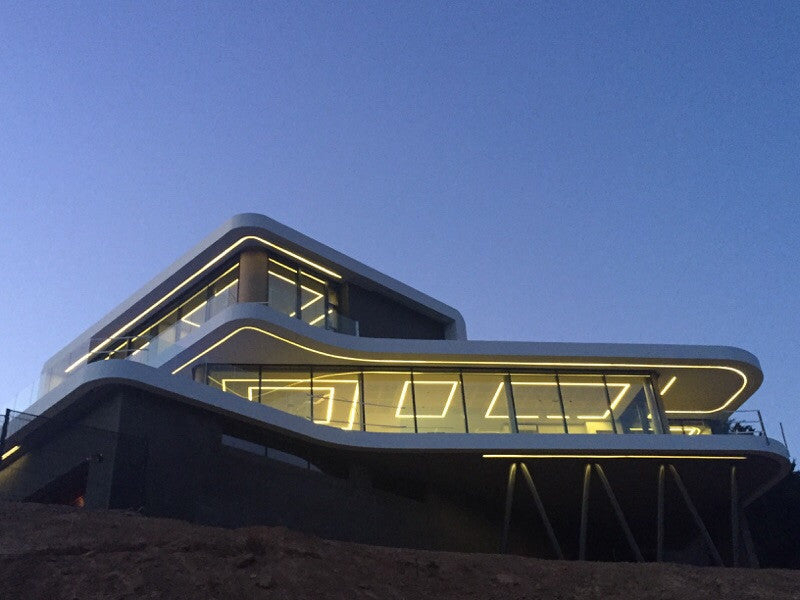 Modern multi-level building at dusk featuring integrated architectural LED lighting along the curved exterior edges