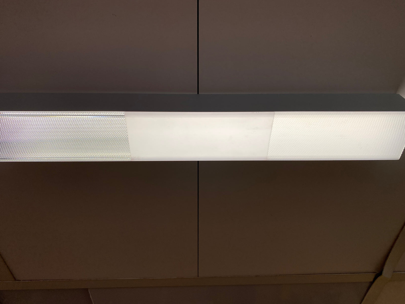 Ceiling-mounted LED fixture displaying a side-by-side comparison of different PL55 diffuser covers with varying light diffusion patterns