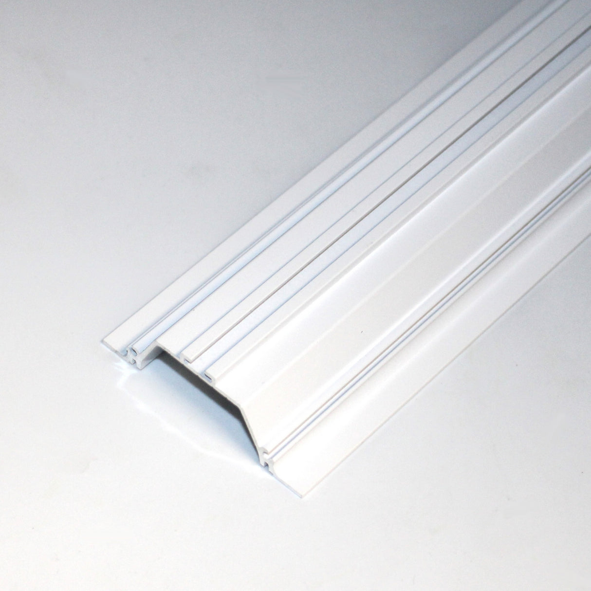 The Shallow Ceiling Recessed LED Lighting Channel, Model Amara, is a white, rectangular cover with ridges and raised center, designed to organize and protect wires on flat surfaces—ideal for use as an LED channel.