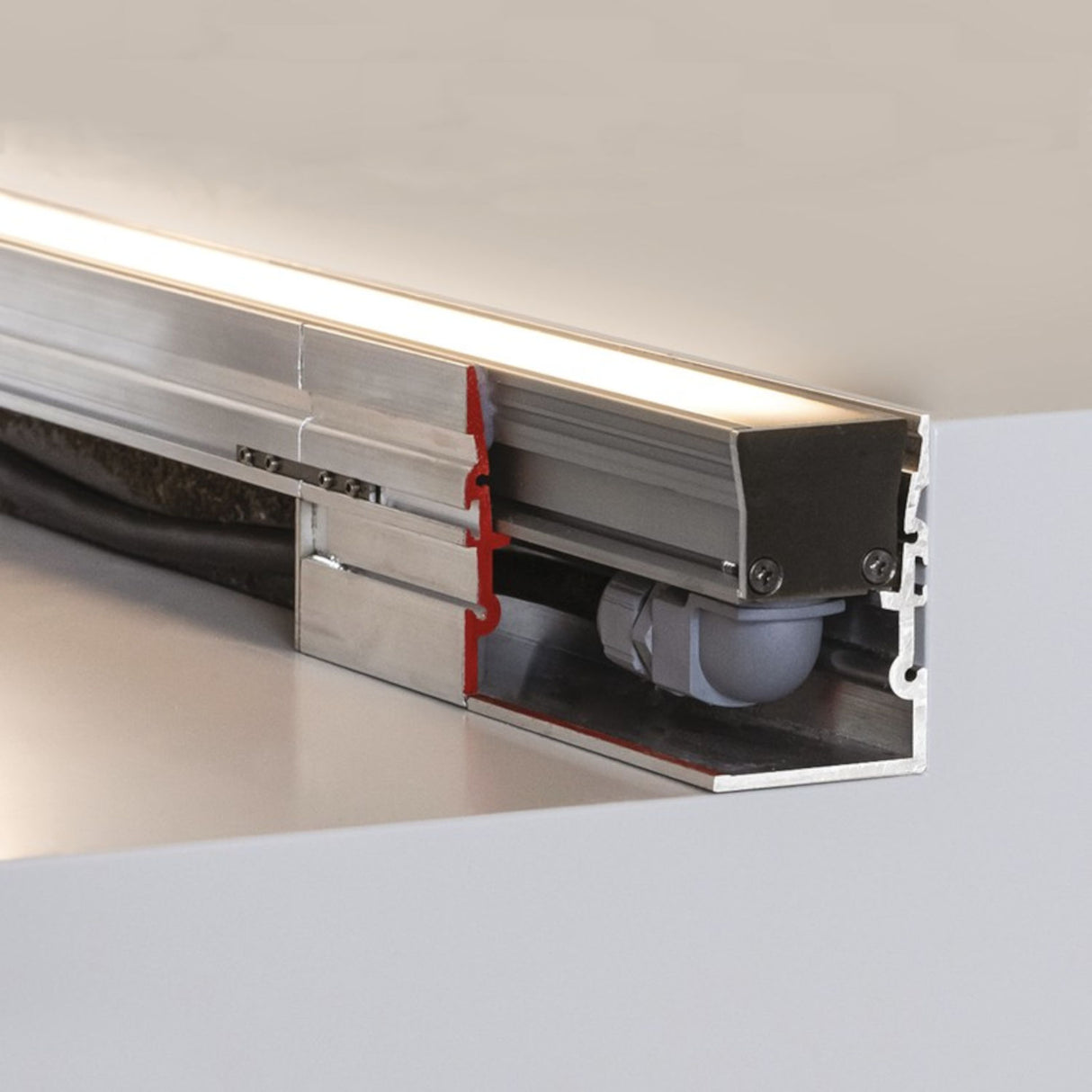 Close-up of a Klus HR-MAX Indoor-Outdoor Driveway Lighting Channel System cross-section with exposed internal wiring and metal housing, installed under a smooth, light surface—ideal for versatile under-cabinet or driveway lighting.