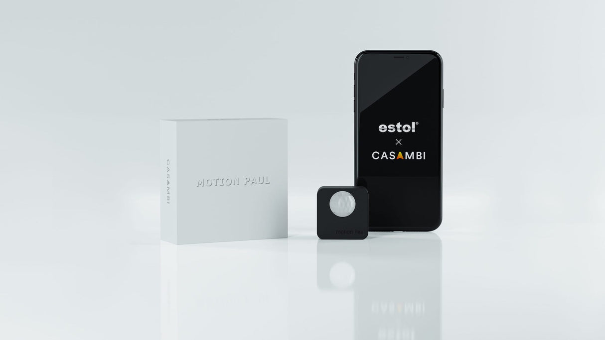 A white box labeled Estol Motion Paul, a compact black Battery Powered Motion Sensor for Casambi Lighting, and a smartphone showing estol x CASAMBI are displayed on a reflective white surface for automatic lighting control.