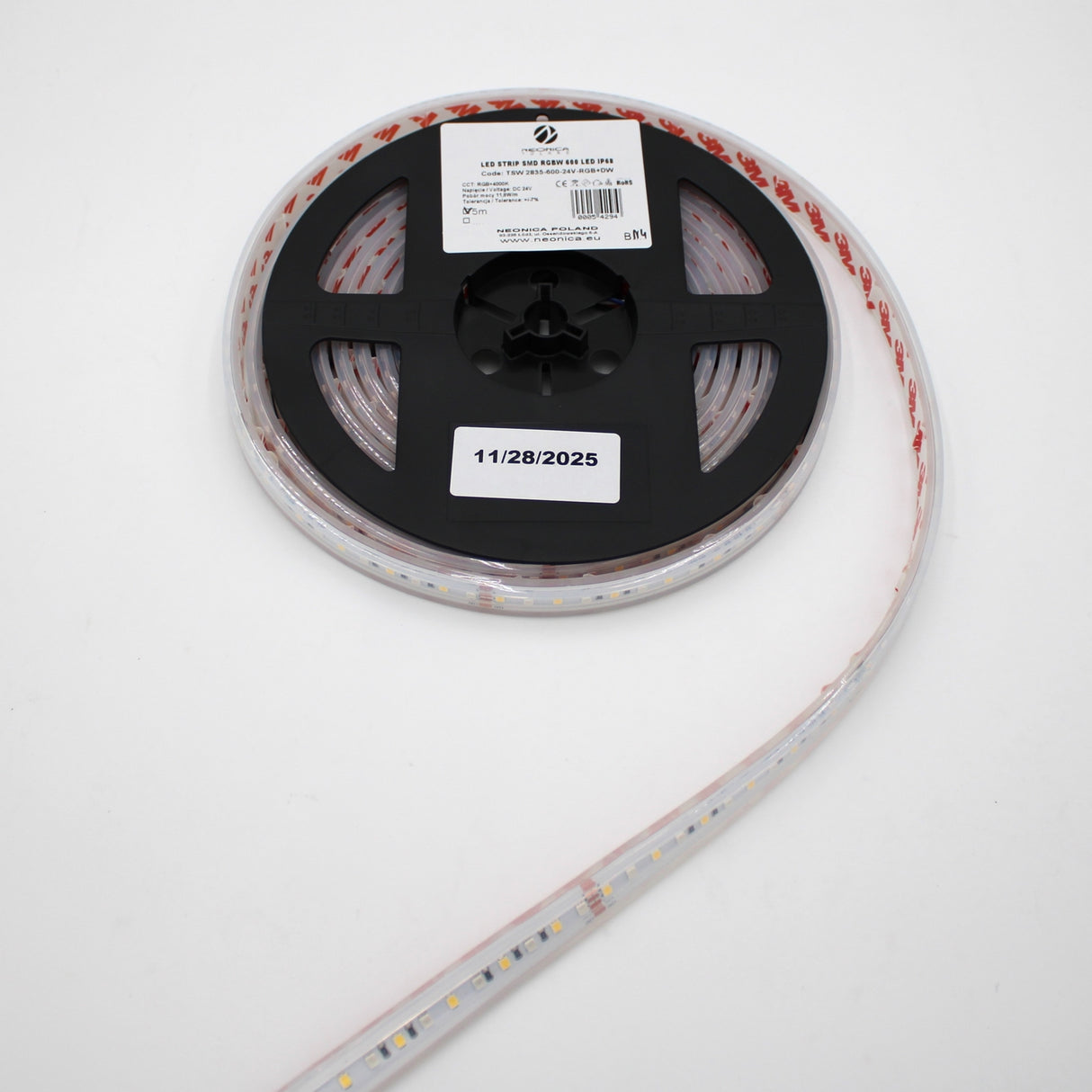 A roll of Low-Power RGBW IP67 Waterproof LED Strip (24V) ~ Iris Series is shown on a black plastic spool with a white label dated 11/28/2025, with the LED strip extending from the reel against a white background.