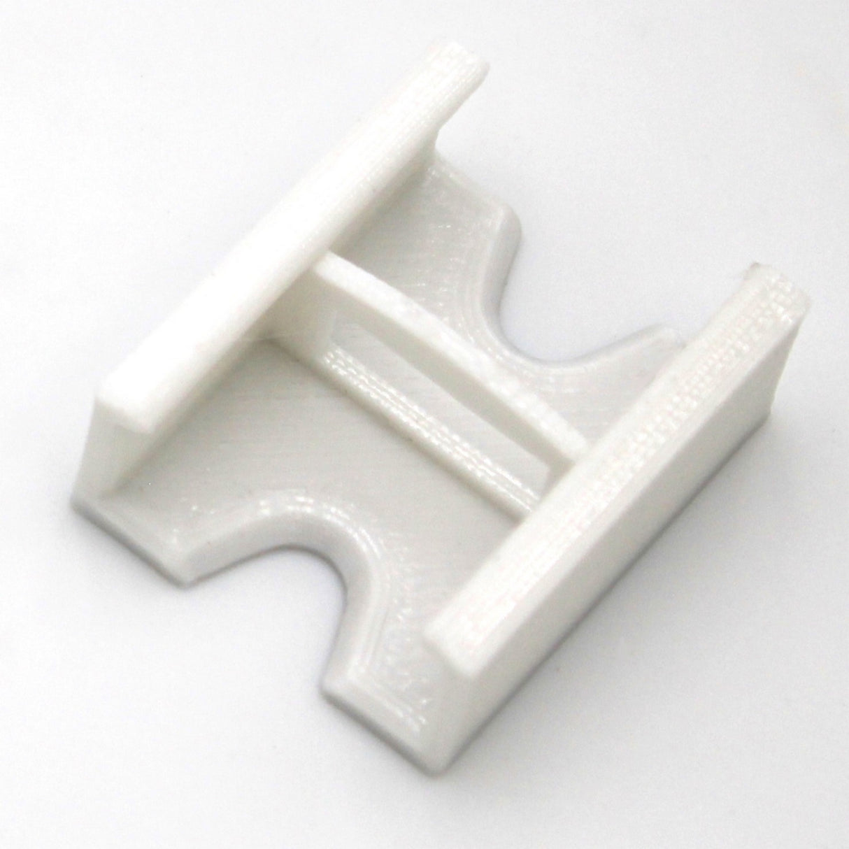A Linear Connector for SL7 Profile, featuring a white plastic body with a rectangular center and two parallel prongs, is displayed on a plain white background.