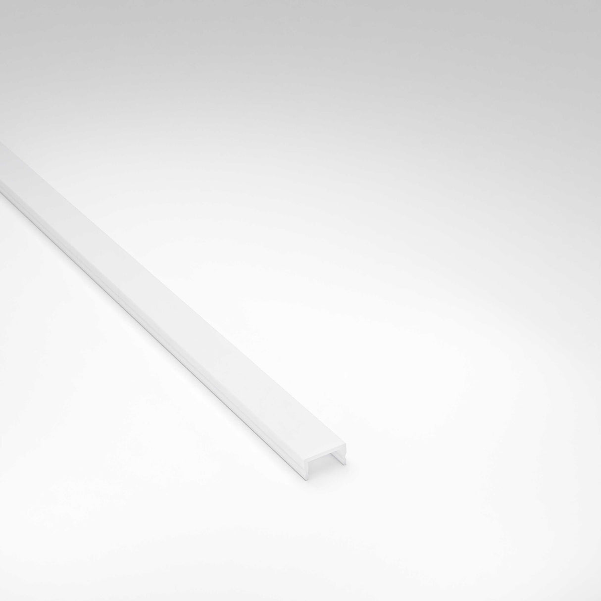 A long, narrow LED Channel Cover for Badalona Profile with an open groove and diffuser is placed diagonally on a plain white background.