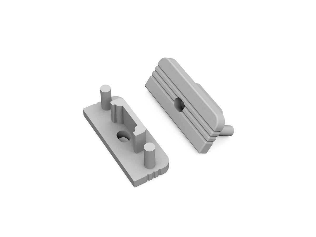 Two gray, rectangular plastic End Caps for the Surface10 Profile—designed as ideal accessories for LED channel installations—feature ridged tops and cylindrical pegs, positioned at different angles on a white background.