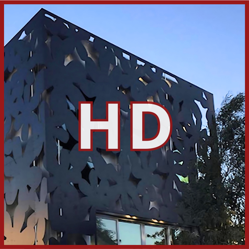 A modern building with a dark, leaf-patterned aluminum facade stands beneath a clear blue sky, partially bordered in red and marked with HD to showcase the Heavy Duty Aluminum Composite Material Panel ~ ALPOLIC/HD Series.
