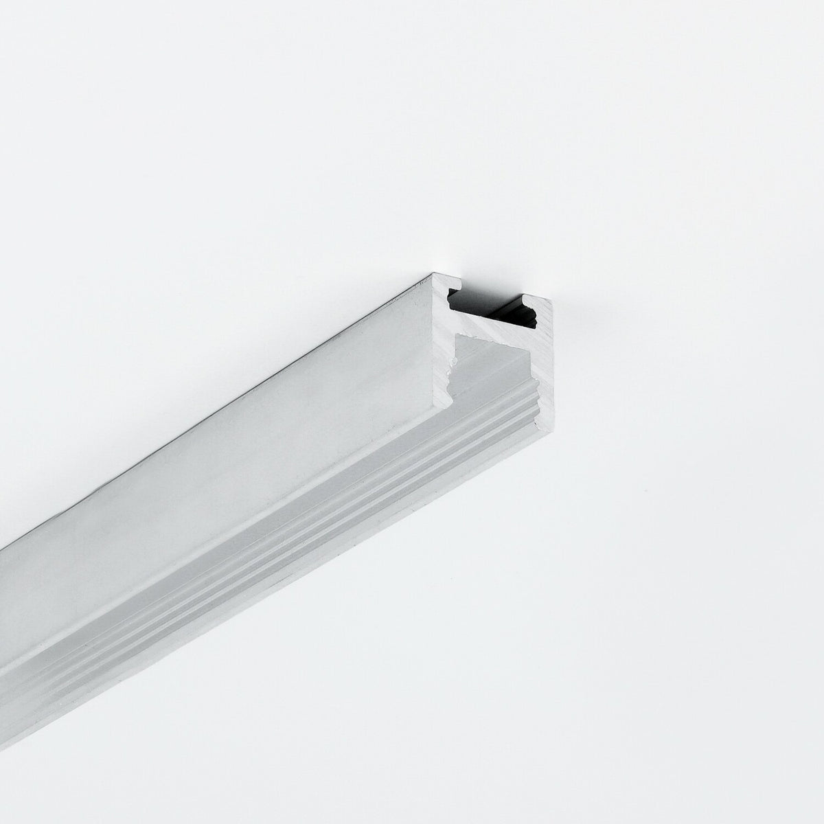 A length of 0.51″ Suspended/Surface Mount Bendable LED Channel ~ Model Bend8 with a silver-toned aluminum grooved profile mounted on a white surface.