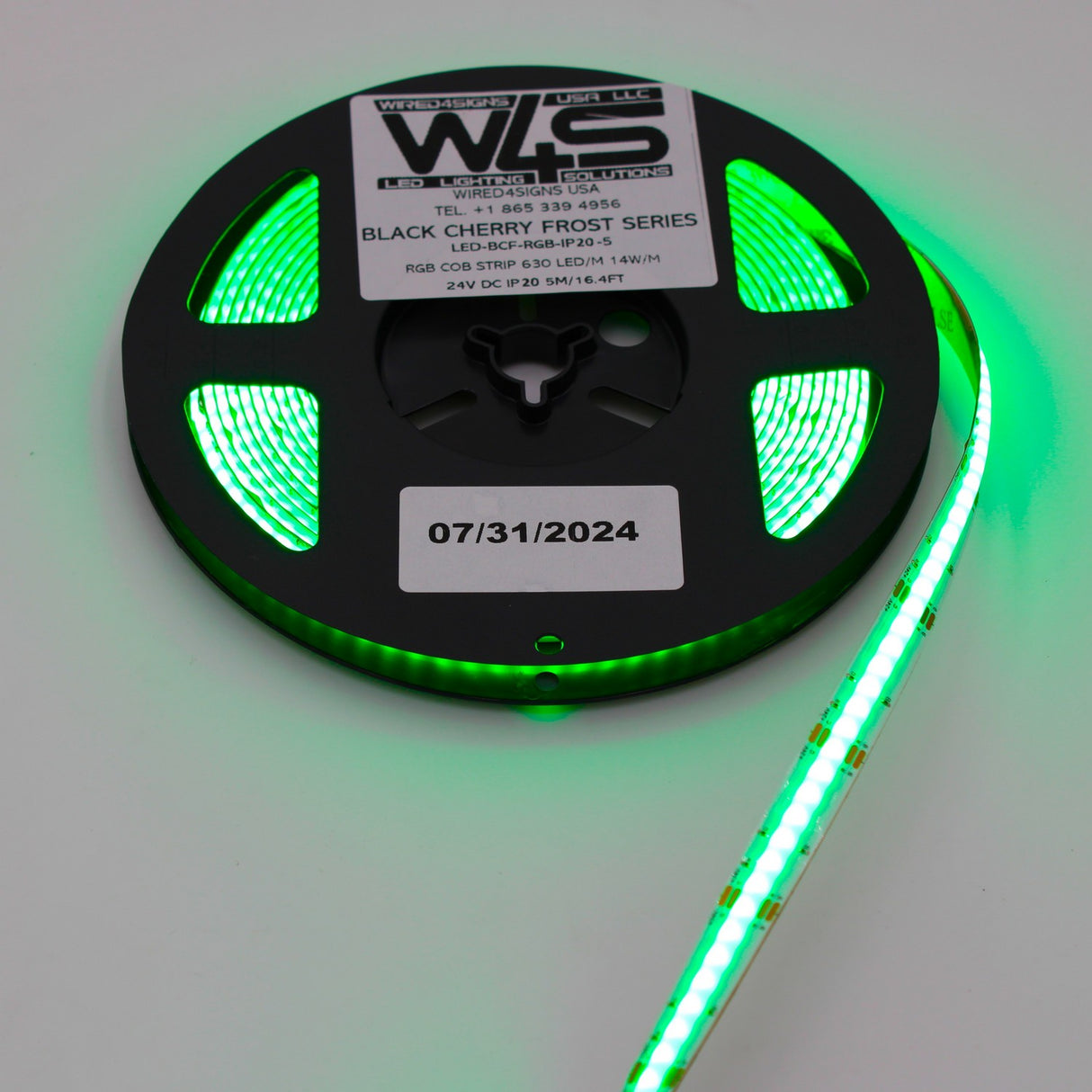 A reel of green flexible RGB COB IP20 LED Strip (24V) from the Black Cherry Frost Series glows brightly, displaying a centered 07/31/2024 date on the label.
