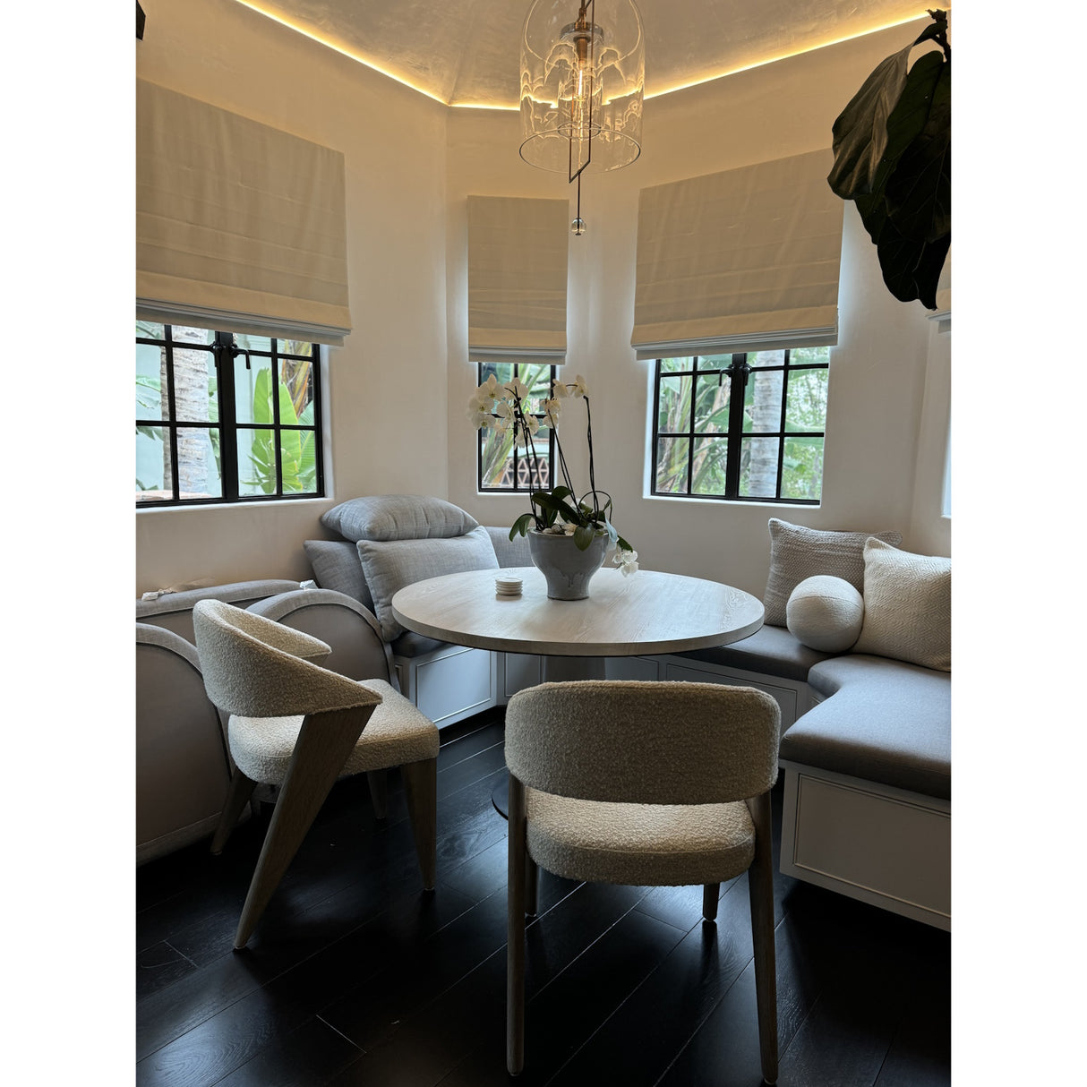 Cozy corner dining nook with a round white table, cushioned benches, modern chairs, orchid centerpiece, and natural light. Continuous COB IP20 LED Strip (24V) ~ White Lily Series adds a soft glow to the neutral decor.