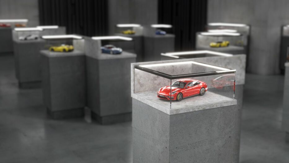 A red sports car model is showcased in a glass case atop a concrete pedestal, while Corner LED Channel ~ Model Cabi12 Duo sleekly illuminates other model car displays throughout the modern, minimalist exhibition space.