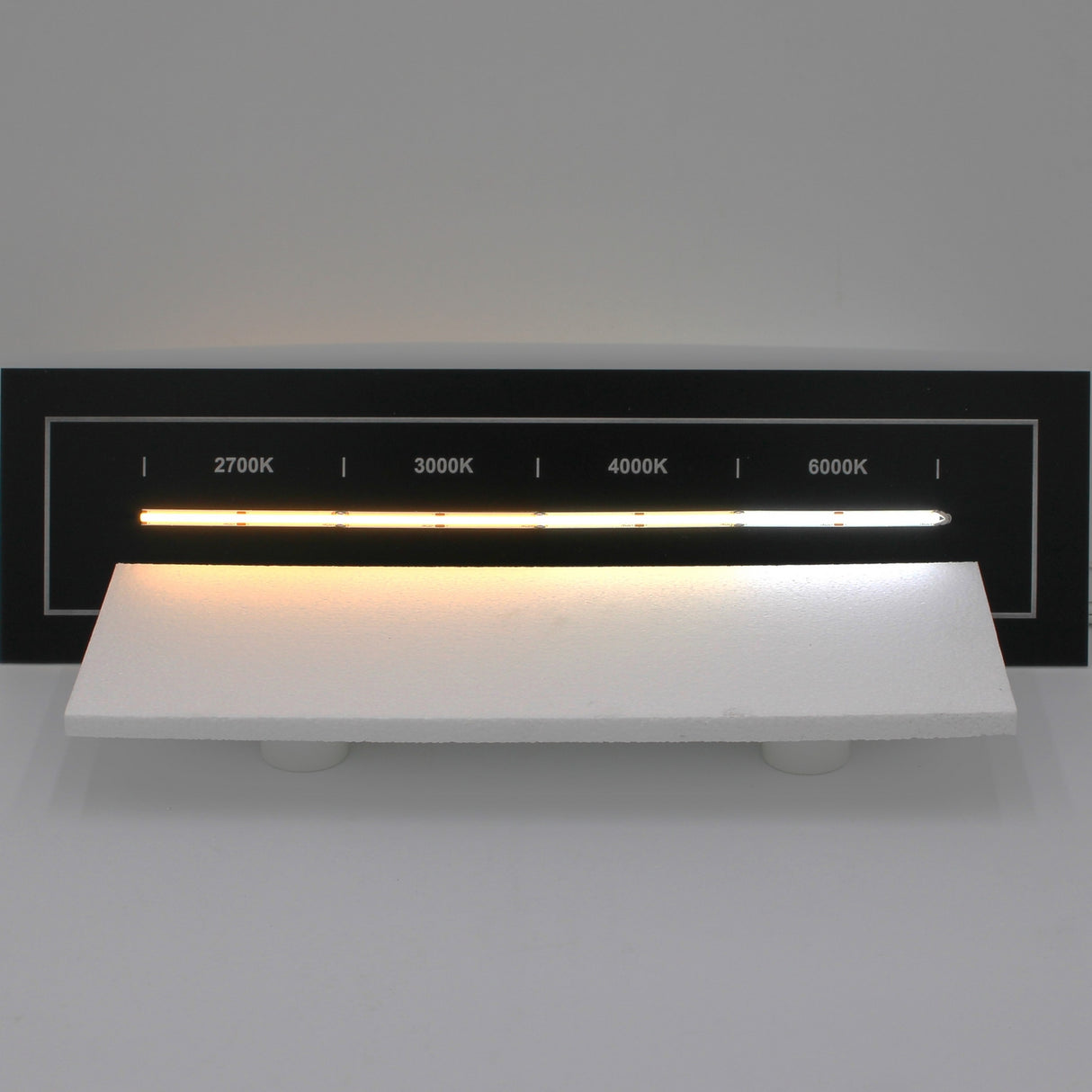 A display showcases the Continuous COB IP20 LED Strip (24V) ~ White Lily Series with five segments, each emitting 2700K, 3000K, 4000K, or 6000K light above a white surface for a smooth transition from warm yellow to cool white.