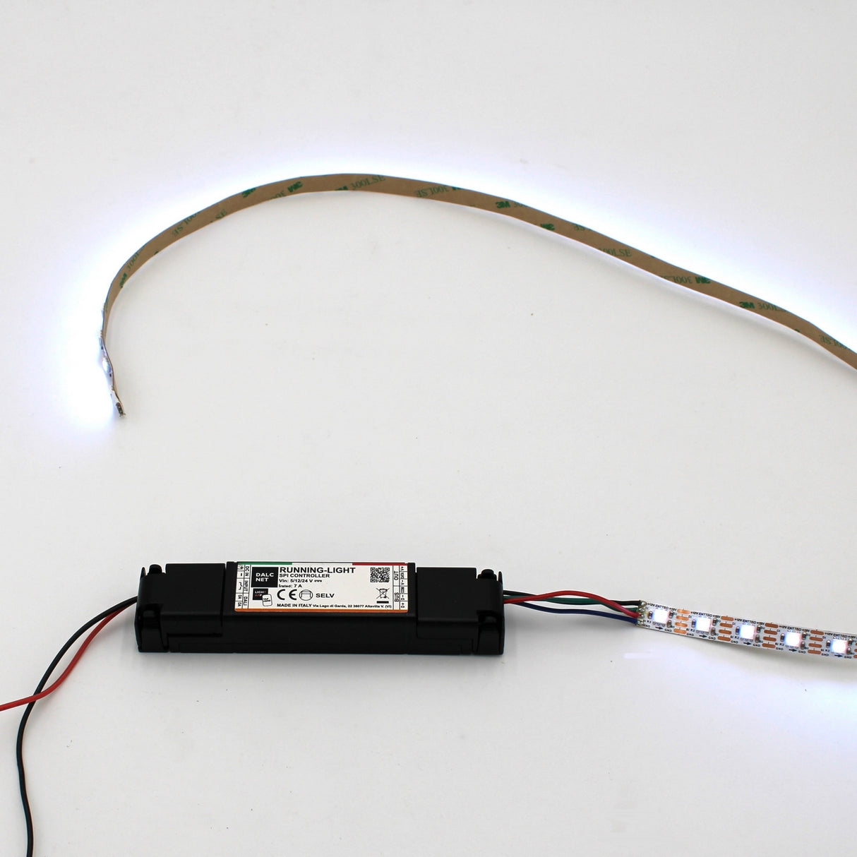 A SPI Controller for Pixel Digital LED Strip (Model RUNNING-LIGHT) with attached wires powers a flexible digital LED strip, which is illuminated and arranged in a curved shape on a plain white background.