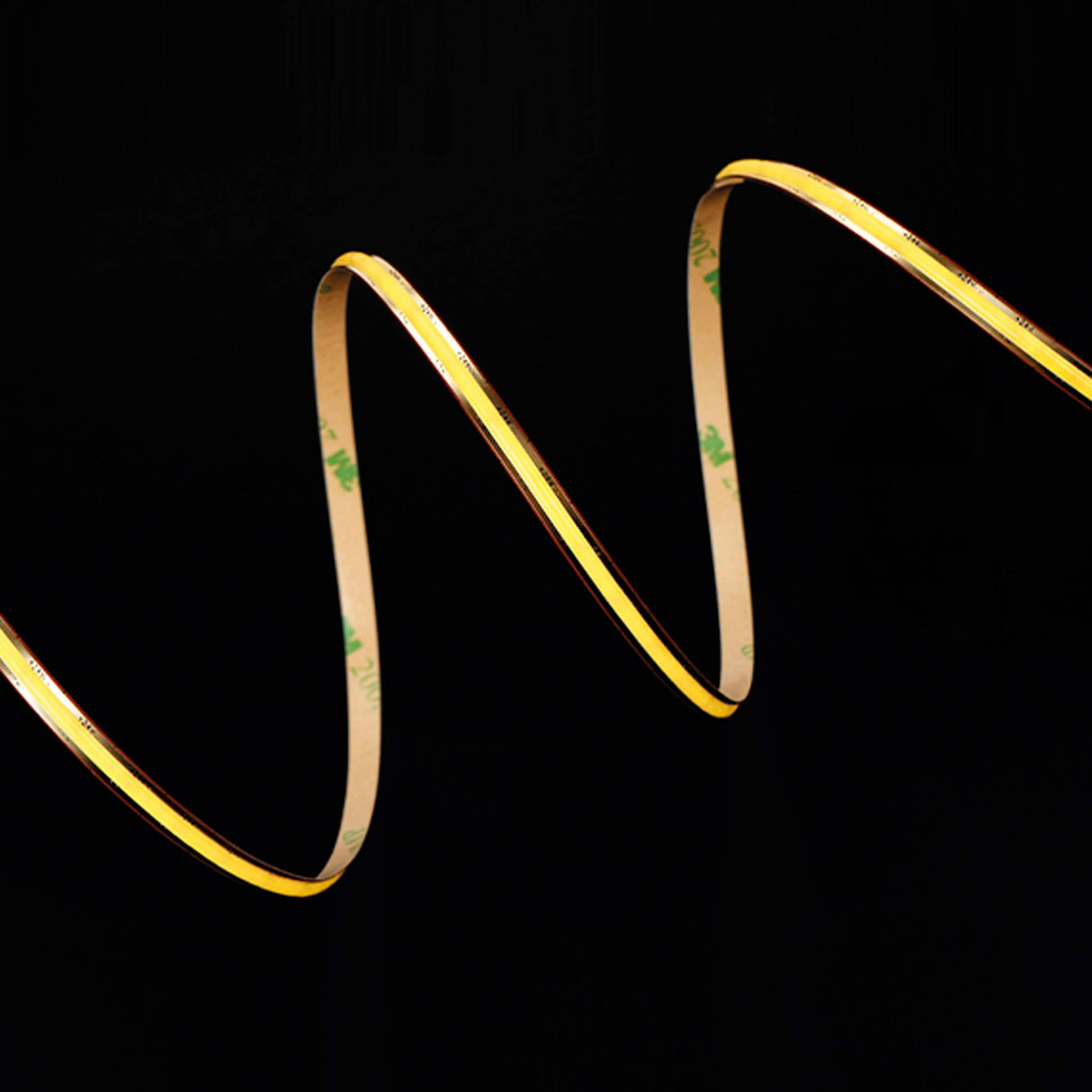 The Narrow COB IP20 High CRI LED Strip (24V) ~ Elite Gold Slim Series bends smoothly in a zigzag wave on a deep black background, its yellow glow and flexible design showcasing COB technology and adhesive backing.