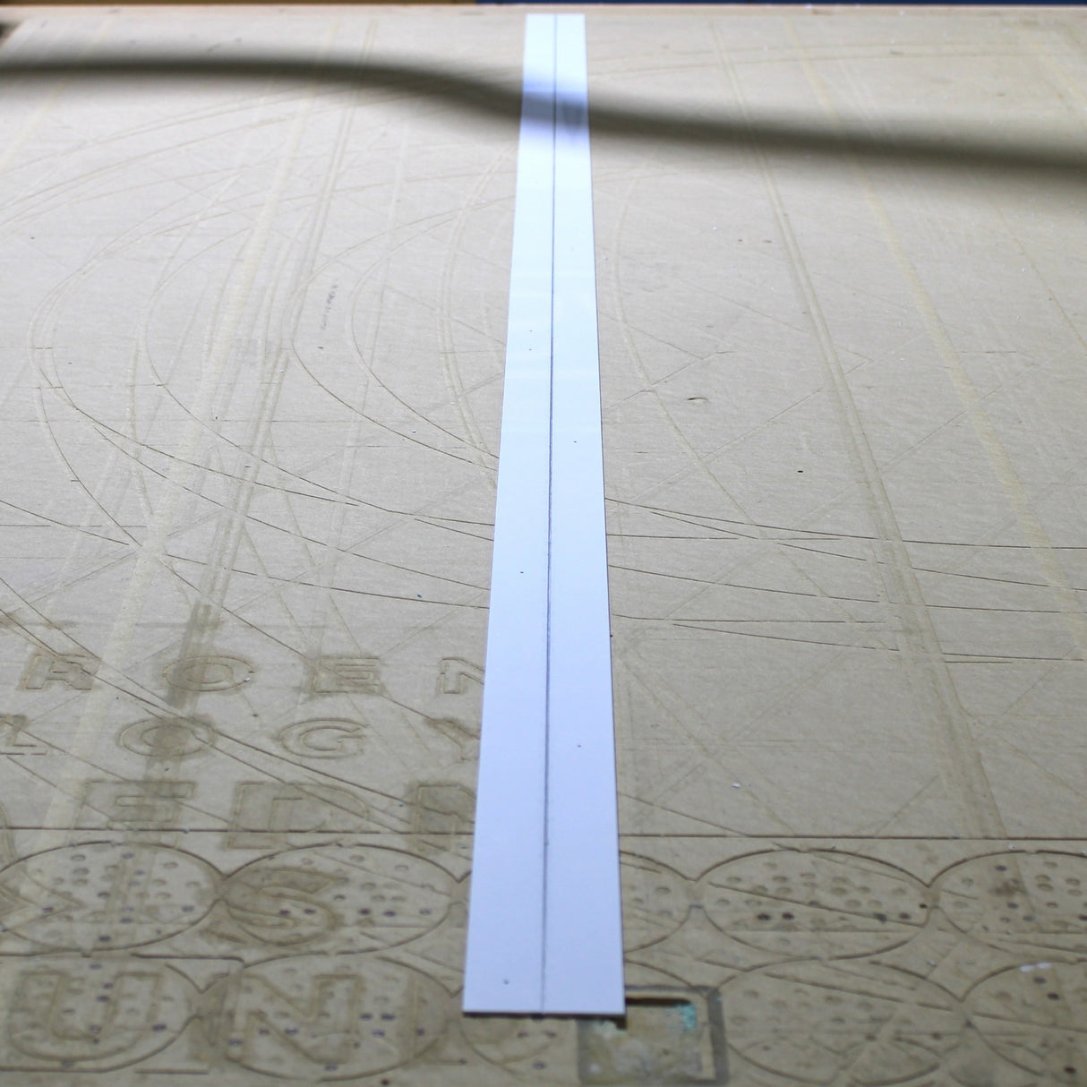 A long, narrow Aluminum Heatsink for Holston74 Profile lies centered on a flat, beige surface with faint engraved lines and symbols in the background.