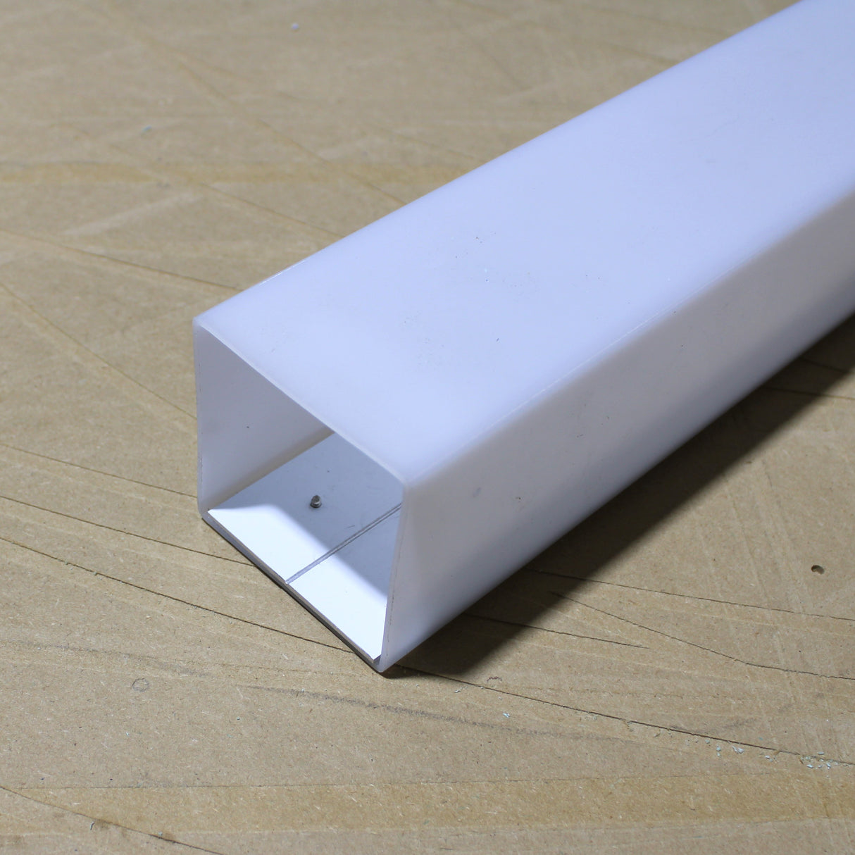 An Aluminum Heatsink for Holston74 Profile rests on a light brown wooden surface with one open end facing the camera.