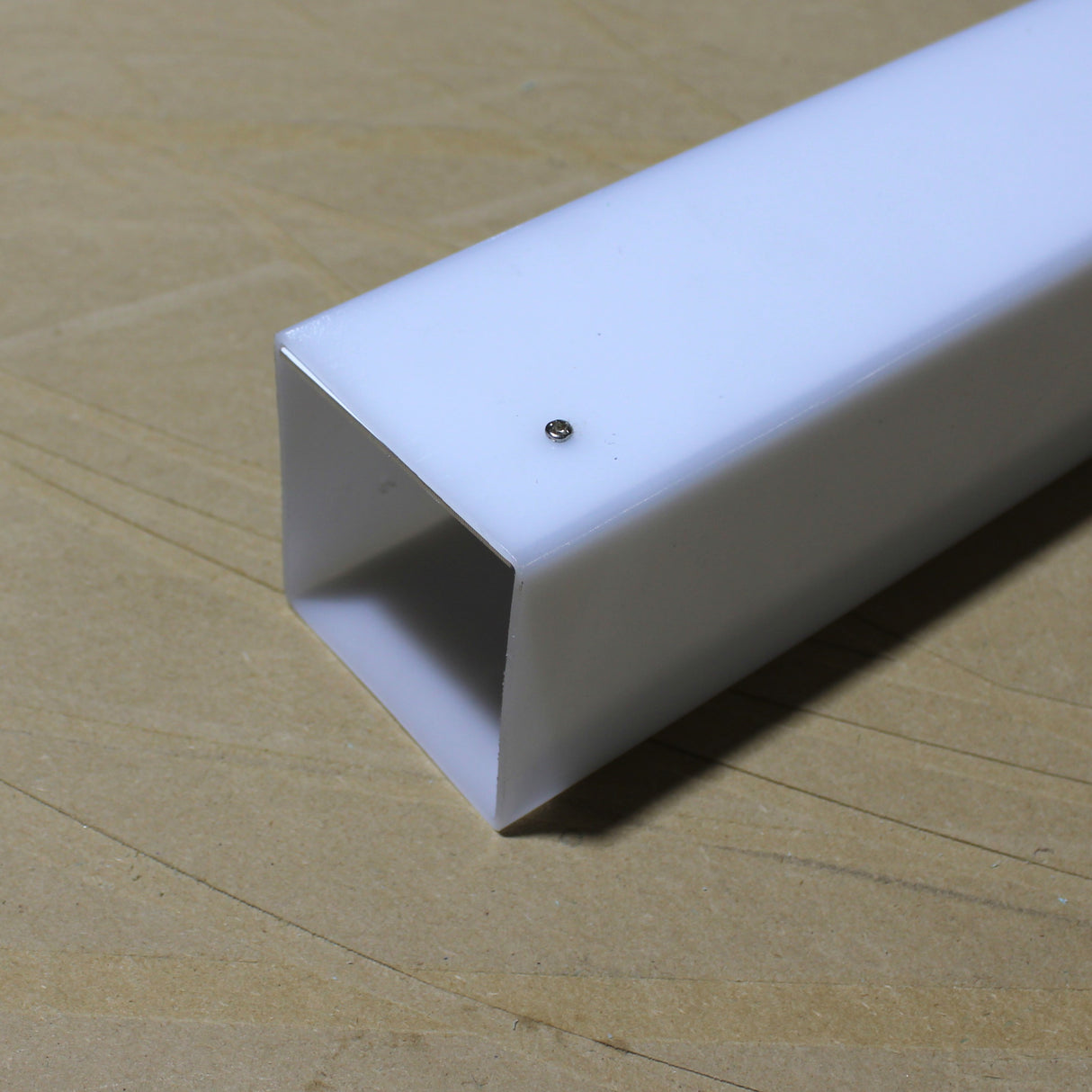 An Aluminum Heatsink for Holston74 Profile, featuring a white rectangular LED diffuser tube with a small screw on its side, is resting on a light wood surface.