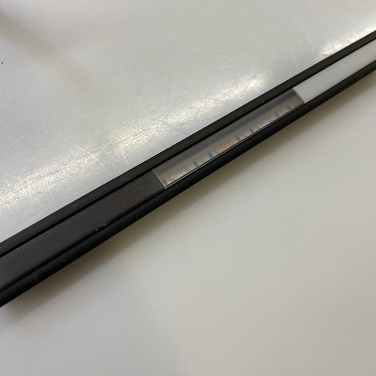 A close-up of the 0.39 Recessed LED Channel ~ Model Smart-In10 with a frosted cover, shown diagonally on a smooth off-white surface for a seamless, dot-free lighting effect.