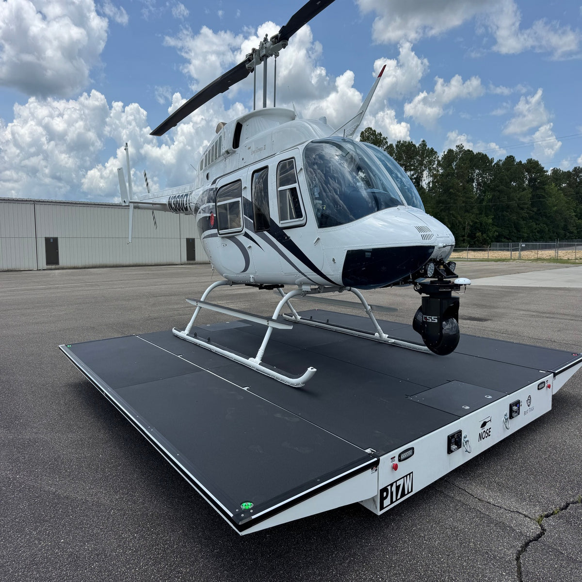 A white helicopter parked on an asphalt lot atop a transport dolly, with Up-and-Down Stair Lighting LED Channel ~ Model Niza Duo profiles visible nearby.