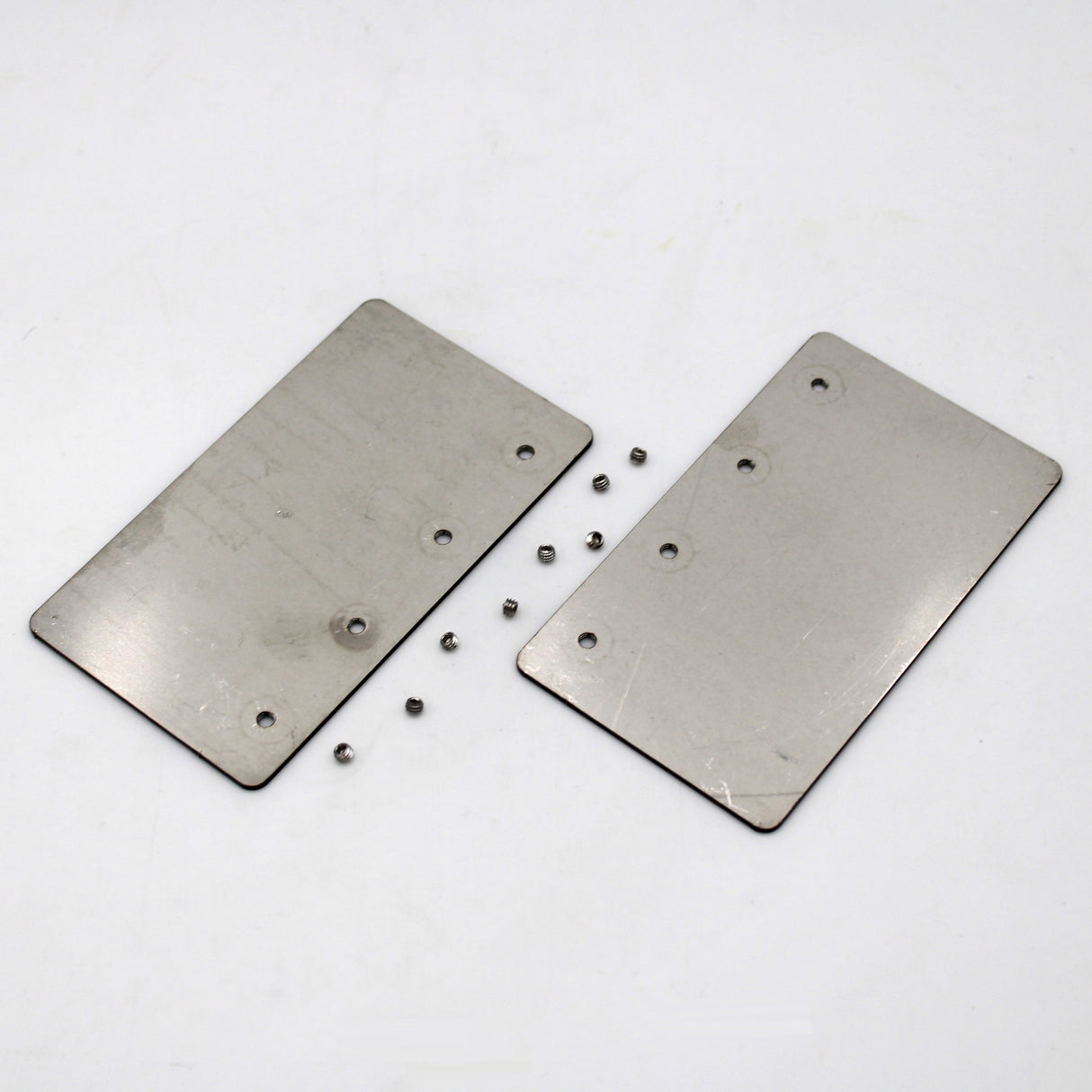 Two Aluminum Straight Joints for Munich Magnum with holes are side by side on a white surface. Several small metal balls are scattered around them, resembling parts from the assembly set.