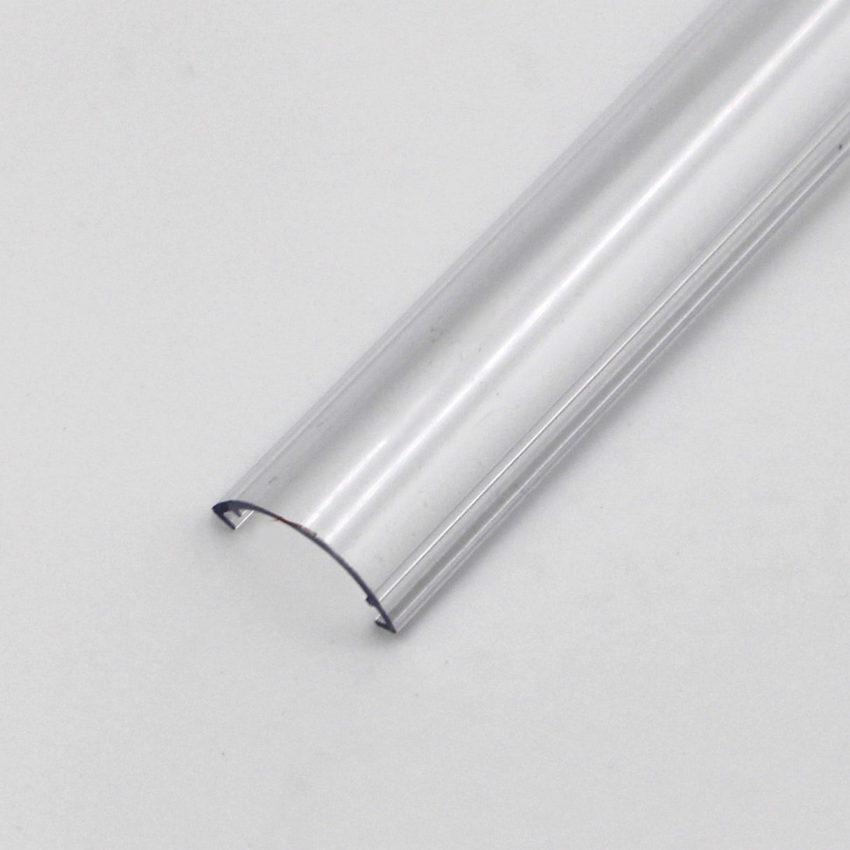 The Diffuser for Alu-Round profile is a clear, semi-circular plastic piece shown resting on a plain white surface with its open side facing down and both ends visible.