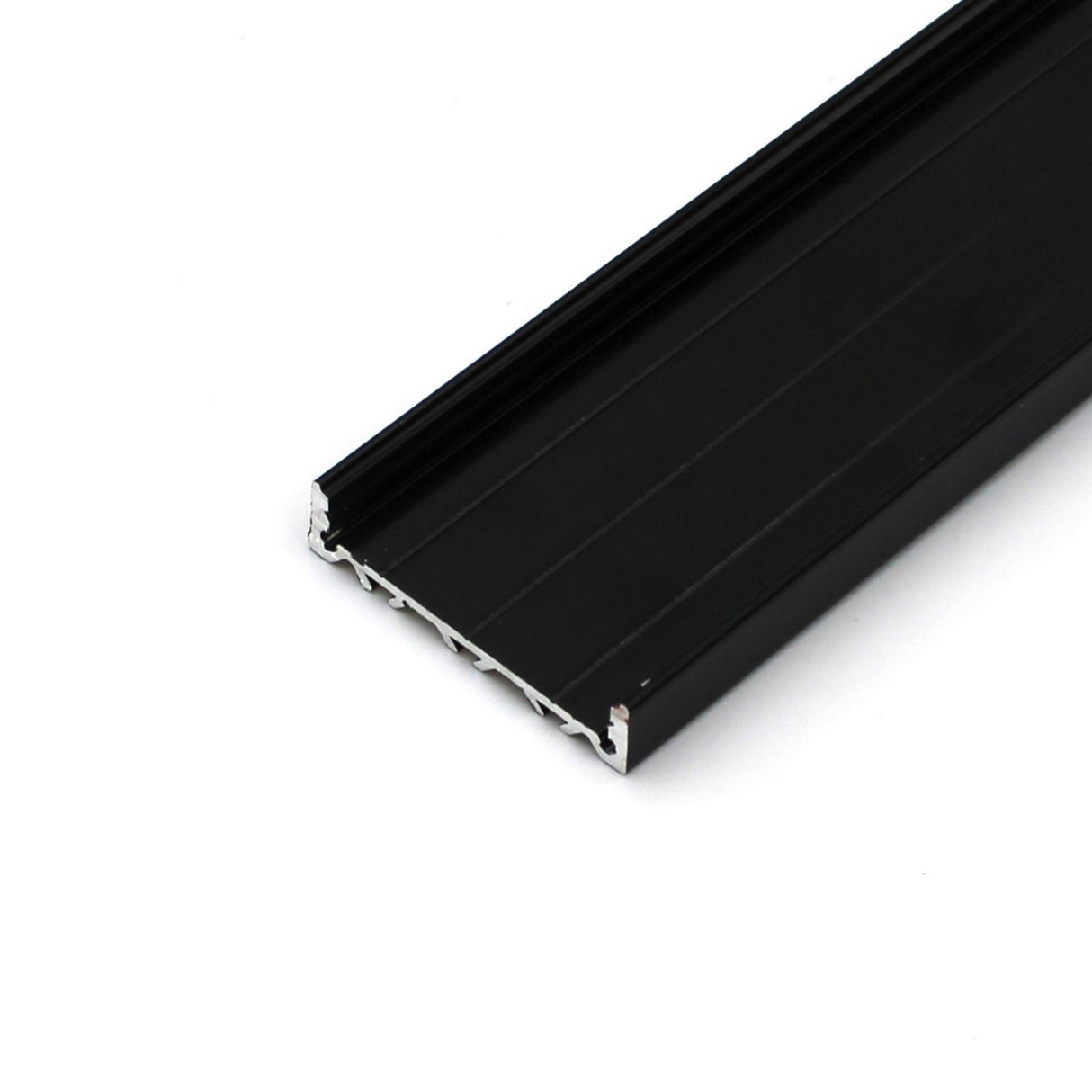 A close-up of the Surface Mount LED Strip Channel ~ Model SLW10, a black rectangular aluminum profile for super wide LED strips, featuring grooves and a flat surface, shown on a white background.
