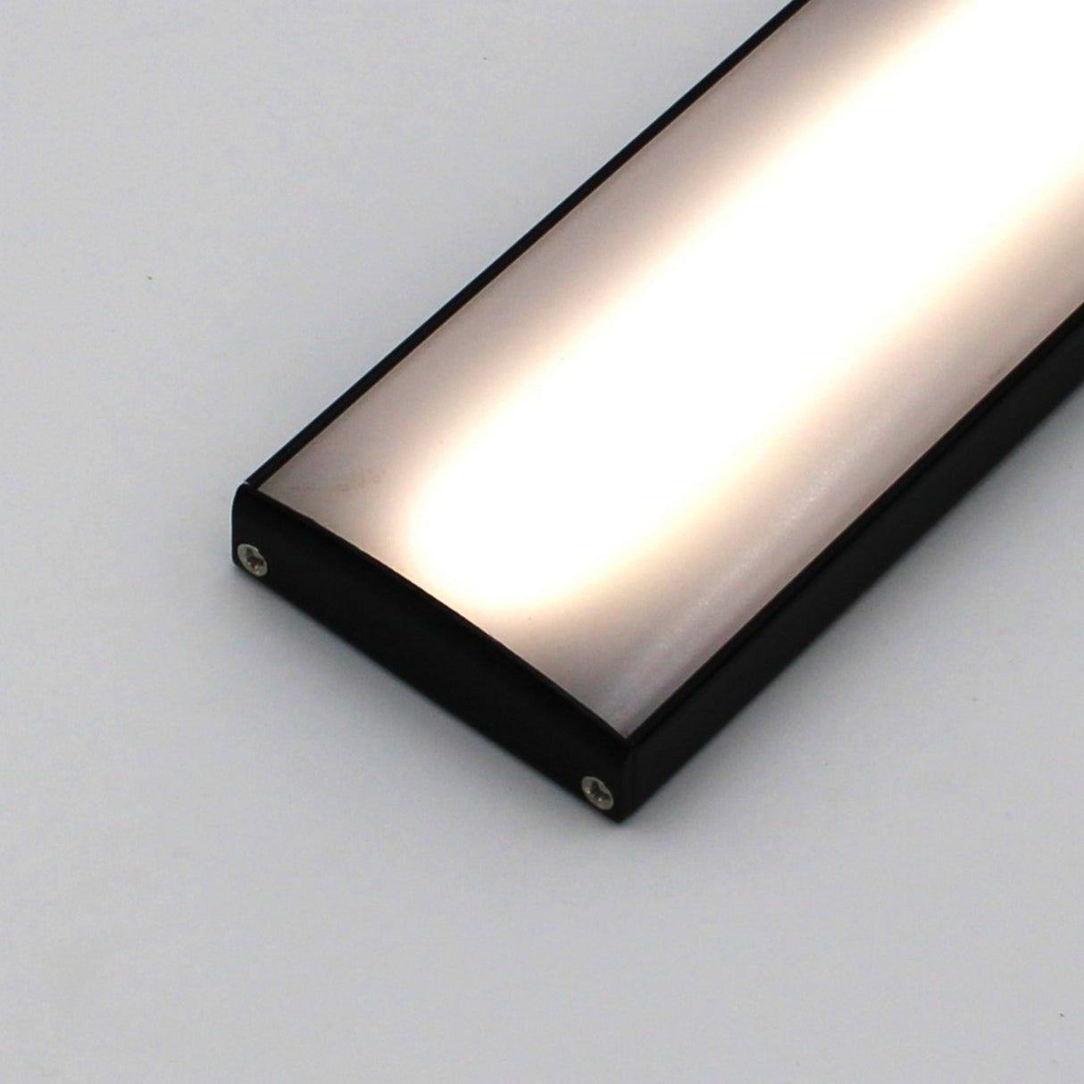 The Surface Mount LED Strip Channel Model SLW10 is a rectangular aluminum LED fixture with a black frame and frosted illuminated cover, shown at an angle on a plain white background.