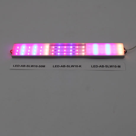 A long, rectangular Diffuser for SLW10 (ALU45-Wide profile) emits pink, purple, and white light. Below it on a white surface are labels: LED-AB-SLW10-50M, LED-AB-SLW10-K, and LED-AB-SLW10-M.