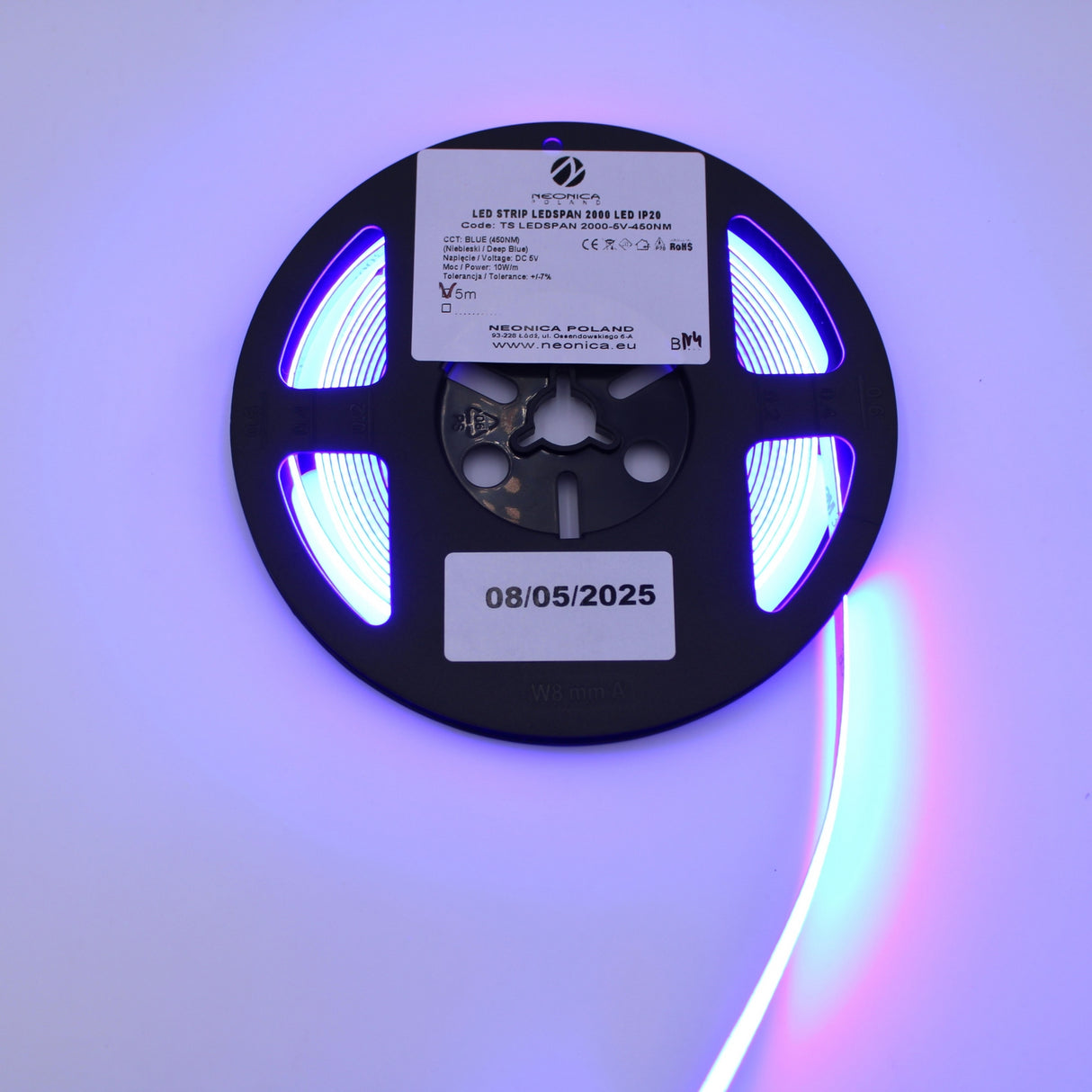 The 450nm COB IP20 LED Strip For Medical Lighting (5V) ~ Aloe Vera Series emits vibrant blue light ideal for phototherapy, features a technical label and a date sticker (08/05/2025), and is shown partially unrolled and brightly glowing.