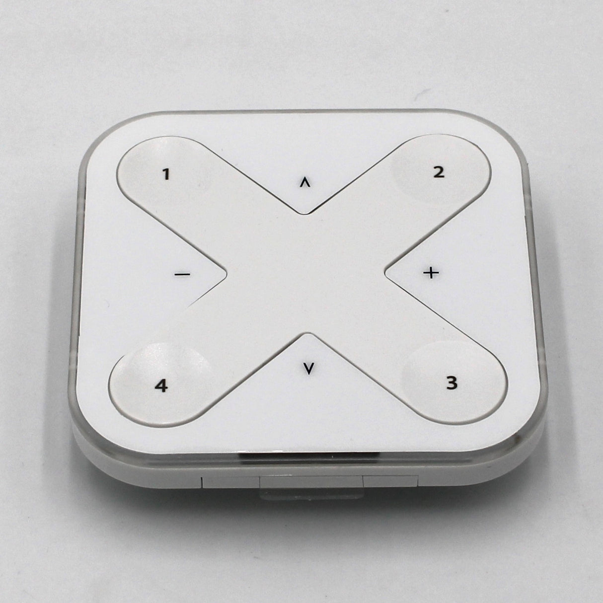 The Casambi basicDIM Bluetooth LED Wall Remote Control ~ Model Xpress-LR is a square, white remote with a large X-shaped button labeled 1-4 and plus/minus and up/down symbols, ideal for wireless lighting control via Casambi Bluetooth.