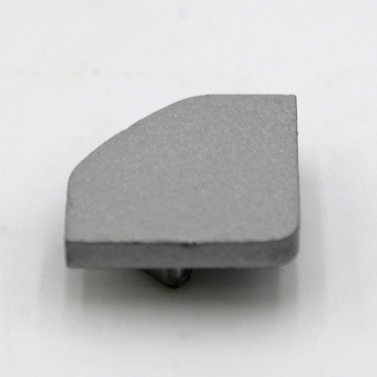 The Single End Cap for LED Channel ~ Alu-45 is a small, flat gray metal cap with an angled edge and bottom peg, shown on a white surface—perfect for completing your Alu-45 lighting fixture.