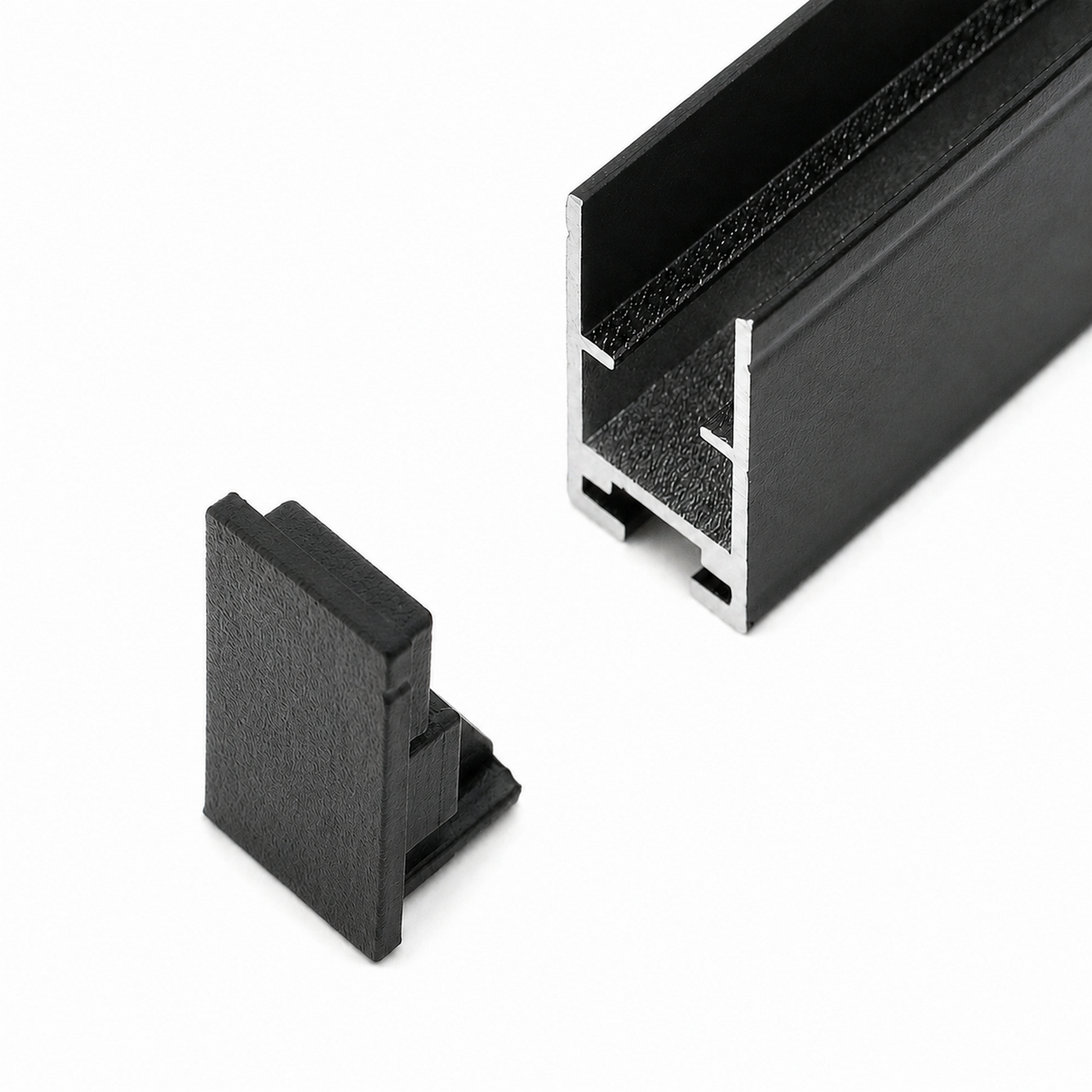 A black Hannover Profile metal channel with a hollow, grooved cross-section is shown on a white background alongside the Plastic End Cap for Hannover Profile in matching black plastic.