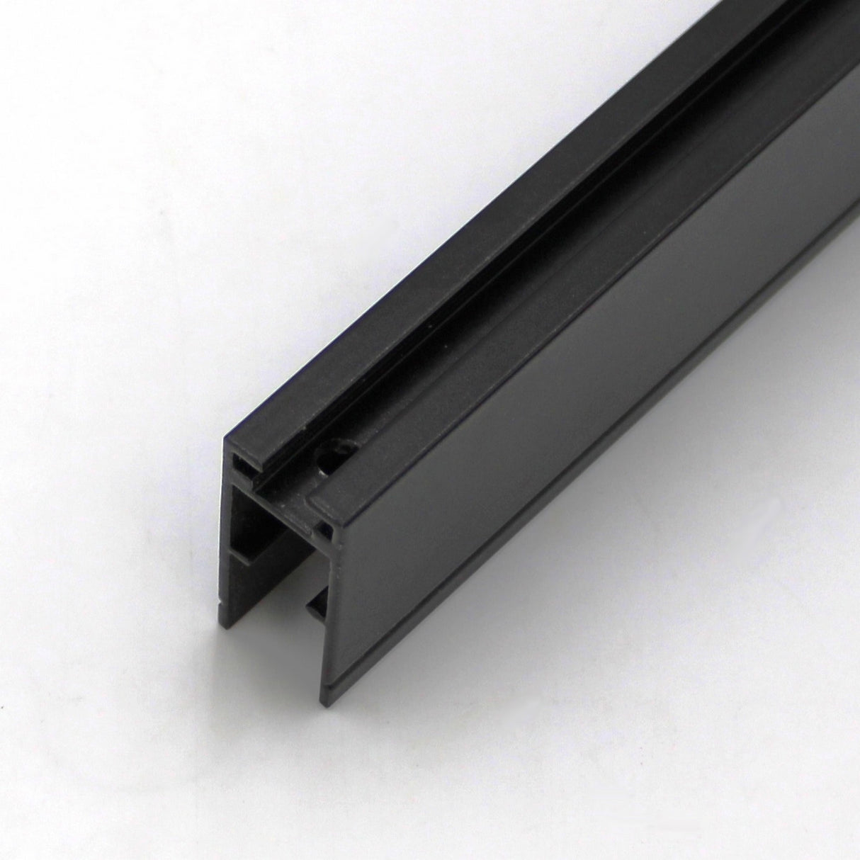 A close-up of the Edge-lit Acrylic Sign Base Channel ~ Model Hannover, a black U-shaped track with grooves, rests on a white surface—ideal for LED edge-lit acrylic signs and other edge-lit signage applications.
