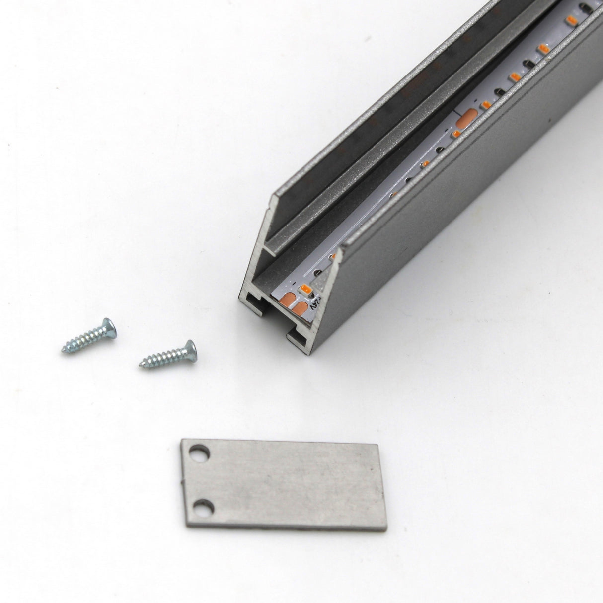 A close-up of the Edge-lit Acrylic Sign Base Channel ~ Model Hannover with an exposed LED strip, a flat metal end cap, and two screws on a white surface—perfect for edge-lit acrylic sign applications.