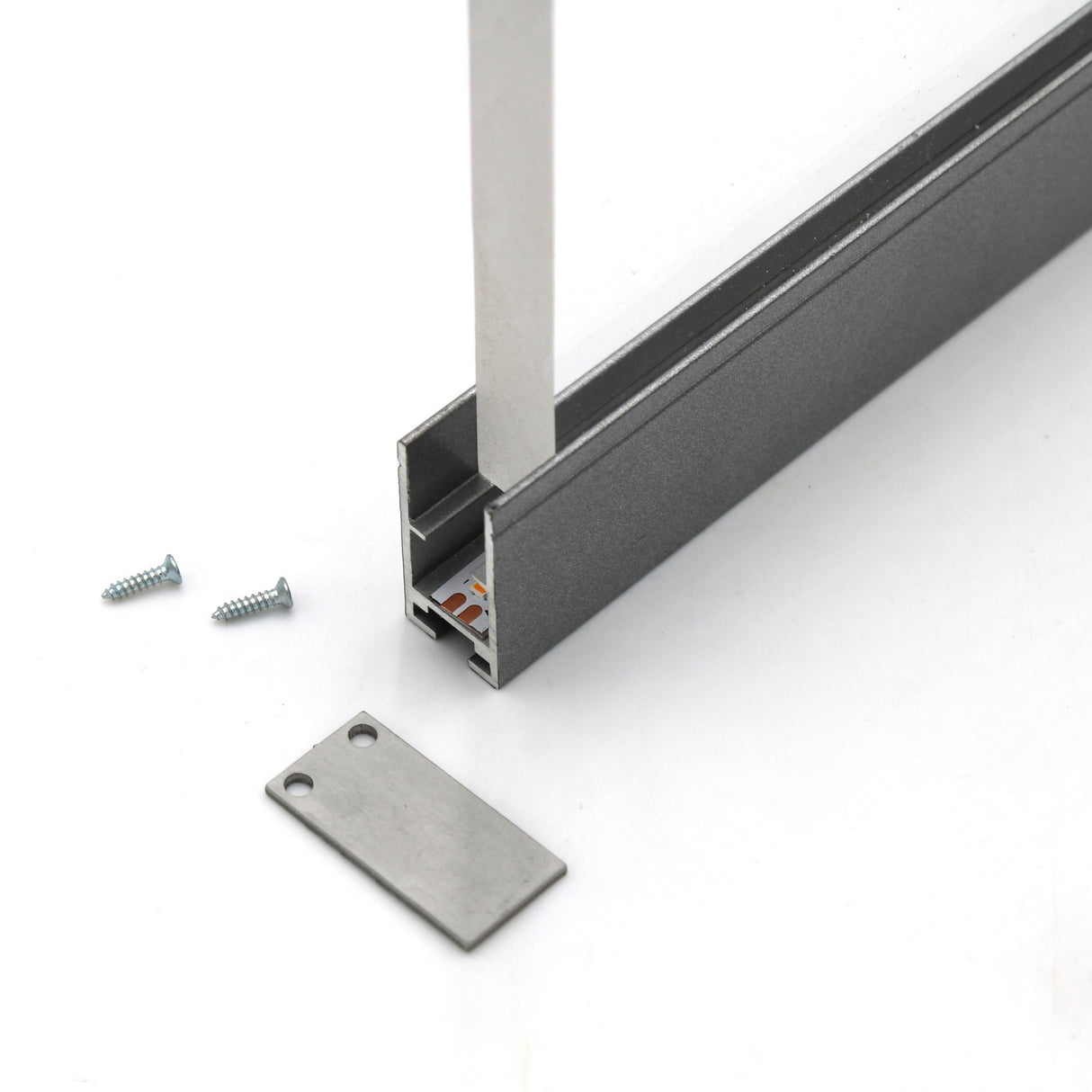 A close-up of the Edge-lit Acrylic Sign Base Channel ~ Model Hannover holding a transparent panel, ideal for acrylic signs, with two screws and a rectangular metal end cap beside it on a white surface.