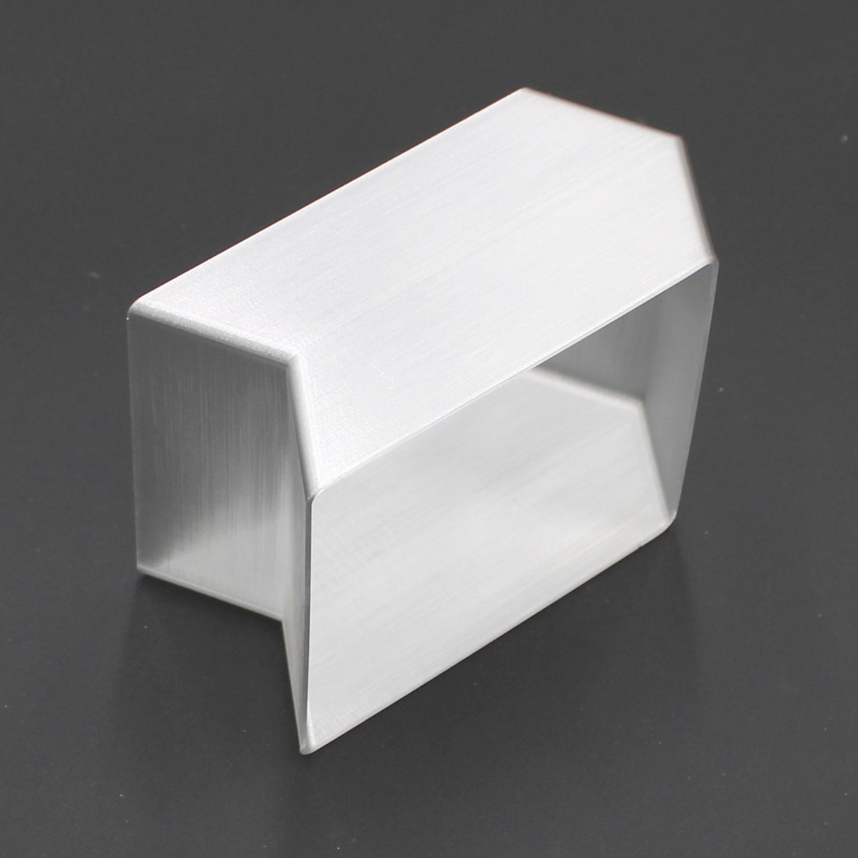 A translucent, angled connector with a rectangular open center rests on a dark surface. Its sleek, geometric form is designed to seamlessly join and showcase the Holston74 profile as a sturdy elbow bracket.