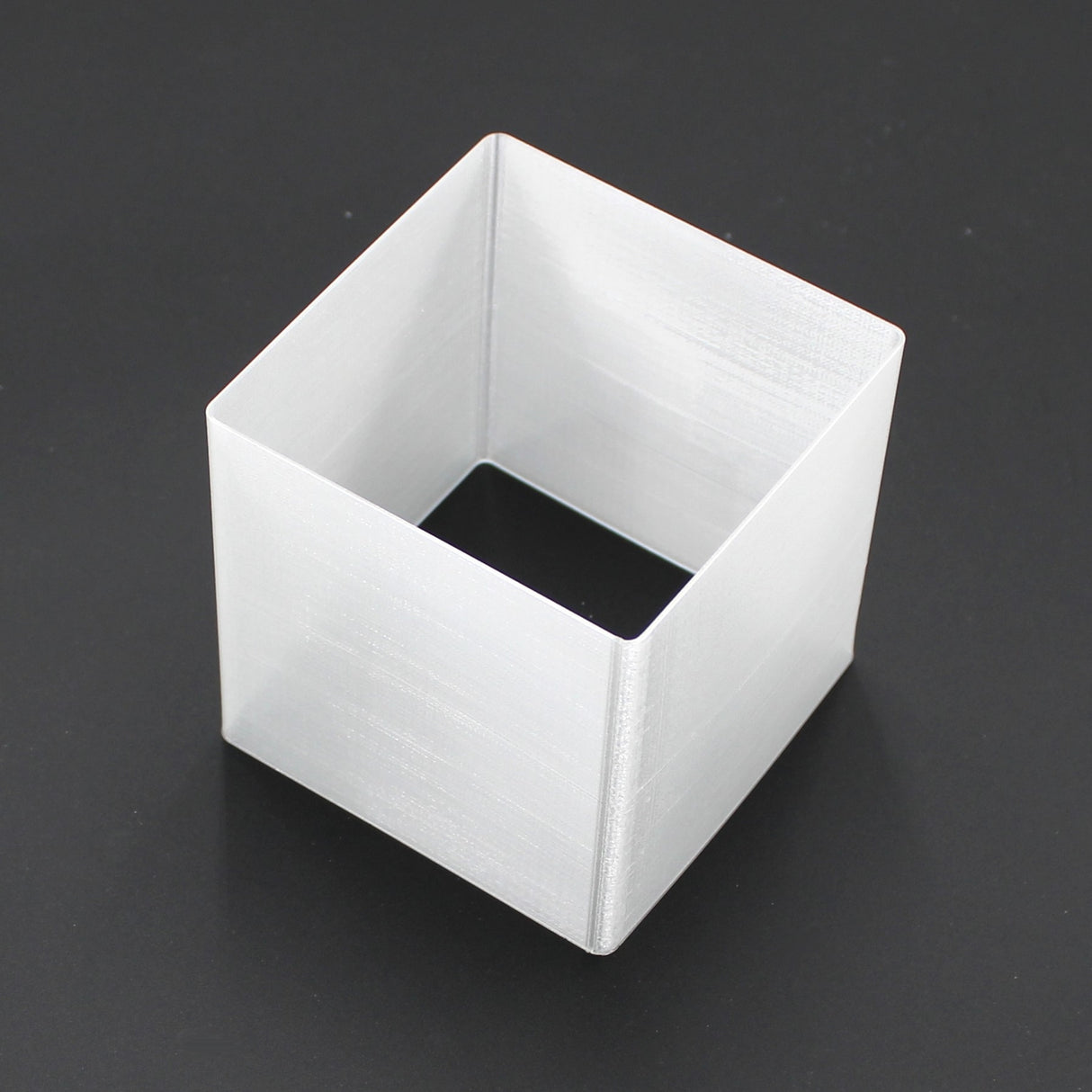 A Translucent Elbow for Holston74 Profile, white and square-shaped with open top and bottom, is placed on a black surface.