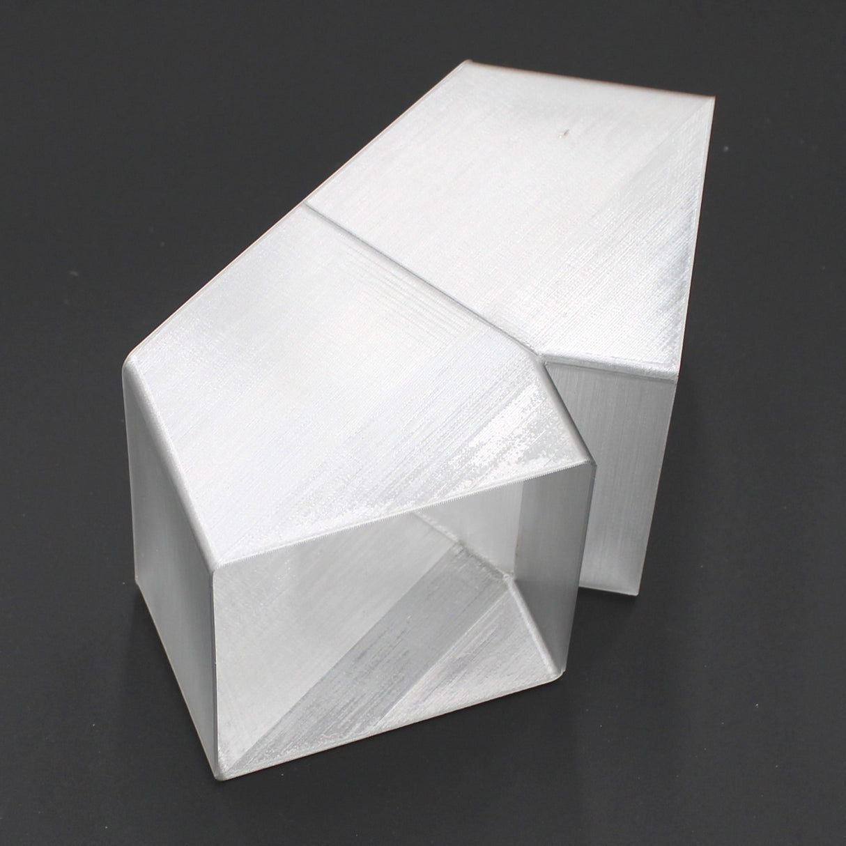 A translucent elbow designed for the Holston74 profile, featuring angular geometric faces and an open hexagonal section, rests on a dark surface.