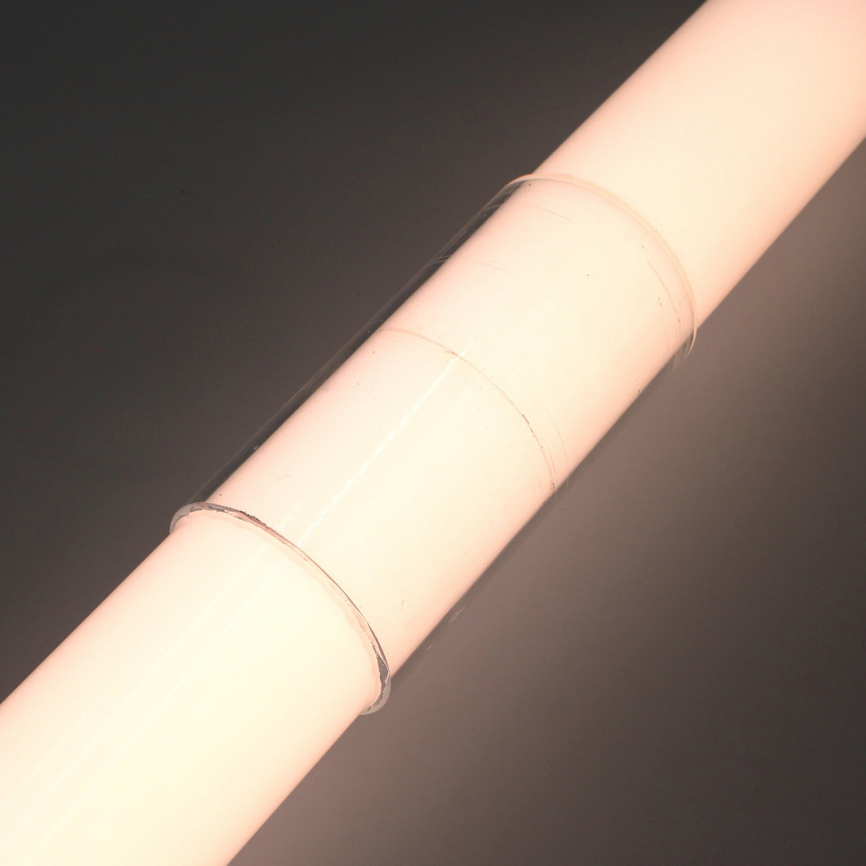 A close-up of a glowing LED diffuser tube joined by the Clear Straight Joint for 2.75" Round Profiles, highlighting round LED profiles against a dark background.