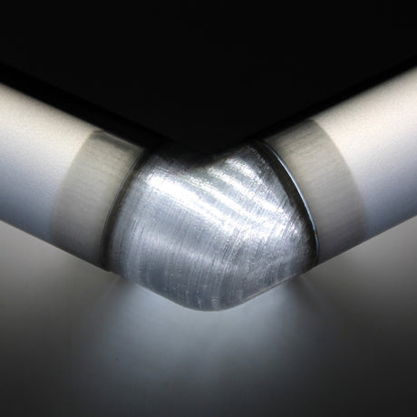 Close-up of a Translucent Elbow for Oslo Profile connecting two sleek, brushed metal surfaces, with soft light reflecting off the smooth texture and rounded corners.