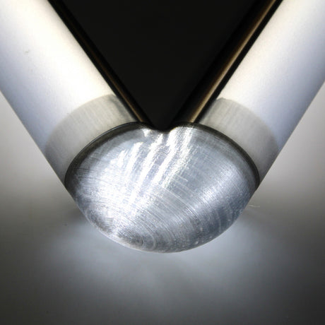 Close-up of a Translucent Elbow for Oslo Profile connecting two cylindrical rods at a right angle, with bright light reflecting off its polished surface.
