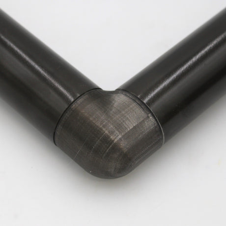 Close-up of two black cylindrical pipes joined at a right angle with a smooth, translucent Translucent Elbow for Oslo Profile connector against a white background.