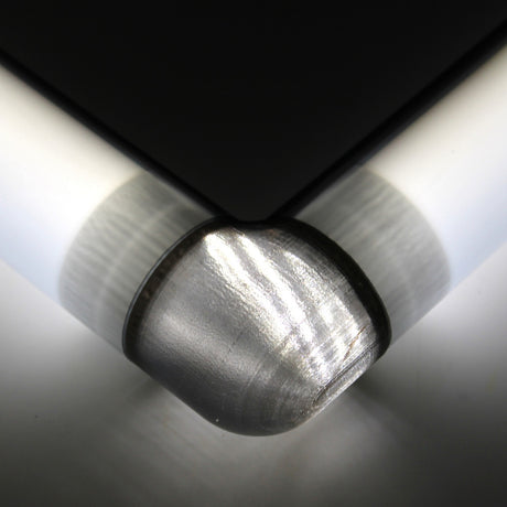 Close-up of a Translucent Elbow for Oslo Profile, featuring a rounded, brushed texture attached to a sleek black and white surface, integrating a 3D print joint and illuminated to emphasize its smooth, reflective finish.