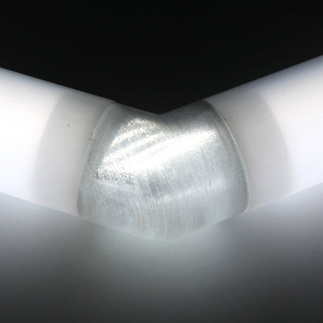 Close-up of a Translucent Elbow for Oslo Profile connecting two white cylindrical tubes at an angle, with bright lighting highlighting reflections on the smooth joint surface.