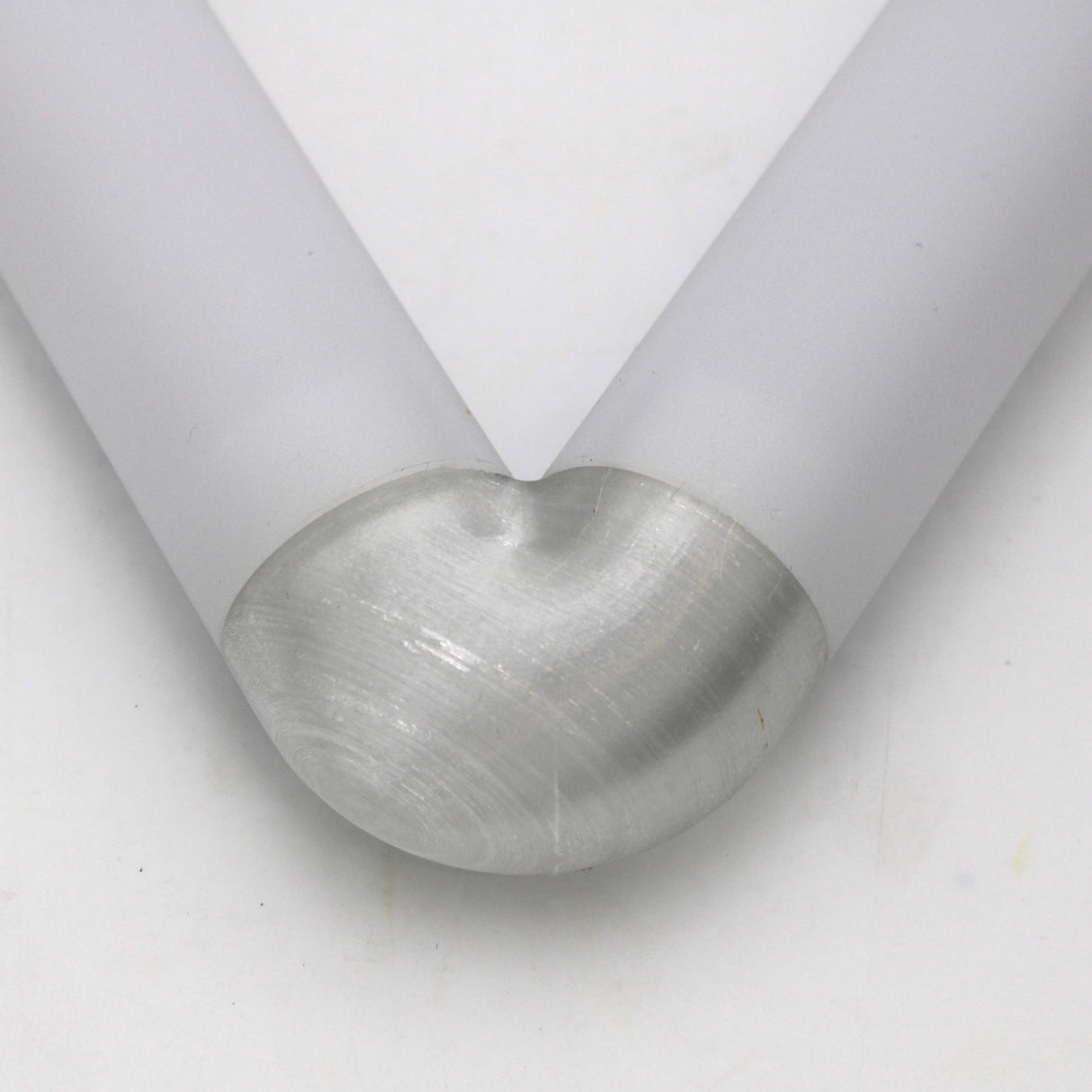 Close-up of two Oslo Profile rods joined at a 90-degree angle by the Translucent Elbow, creating a smooth, rounded corner with a matte silver finish against a plain white background.