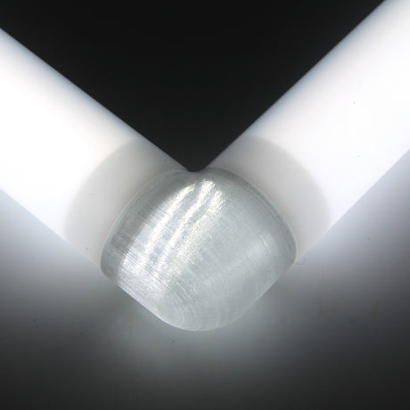 A close-up of two white Oslo Profile rods joined at a right angle by the Translucent Elbow connector, with light illuminating the surfaces and creating soft shadows.