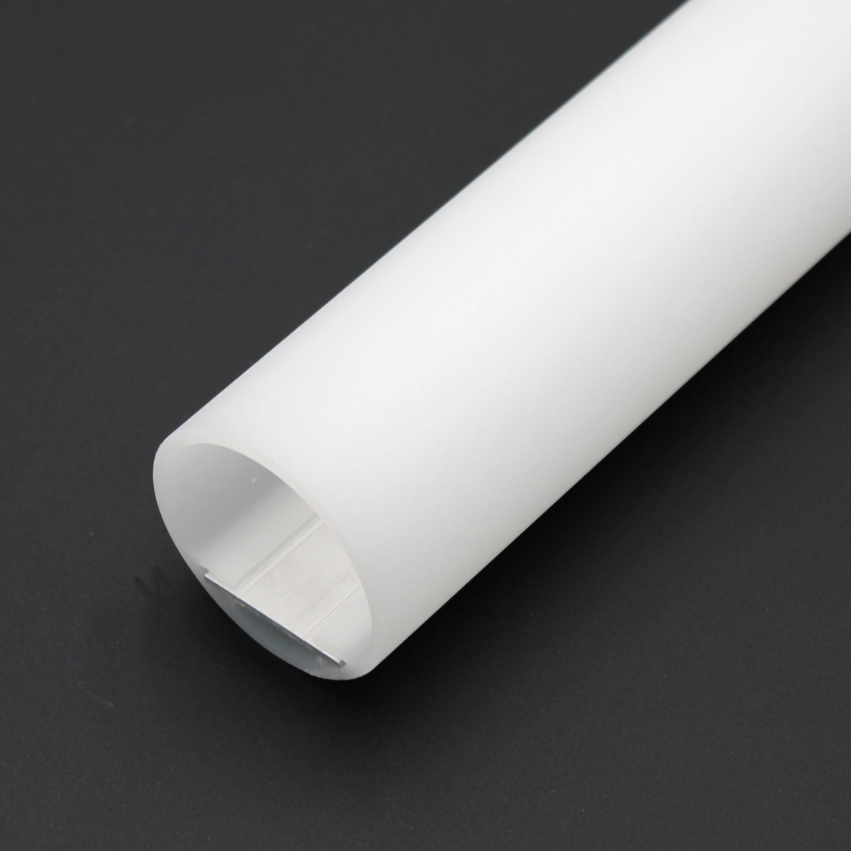 A Round Methacrylate LED Diffuser Tube ~ Model Oslo, featuring a cylindrical frosted white design with an open end, is placed diagonally on a plain black background.