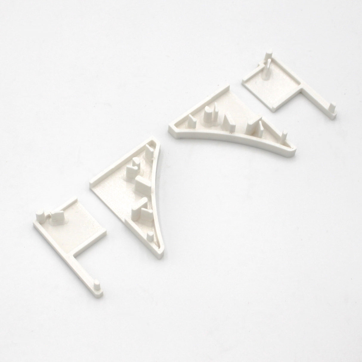 Four small, white End Caps for Pula P10 Profile, each with various raised notches and tabs, displayed in a row on a white background.