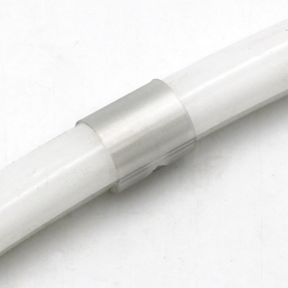 A close-up of a white cable secured with a smooth, metallic clamp and the Translucent Straight Joiner for Neon Redondo XL Profile against a plain white background.