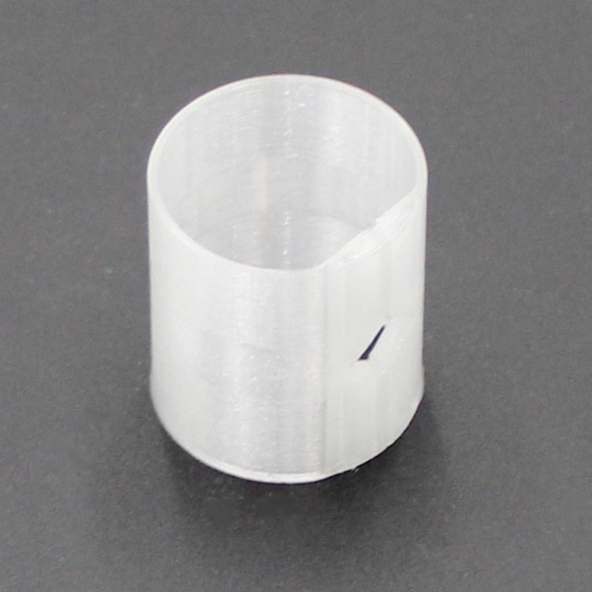 A Translucent Straight Joiner for Neon Redondo XL Profile, featuring a cylindrical shape and a small rectangular cutout on one side, sits on a dark surface.