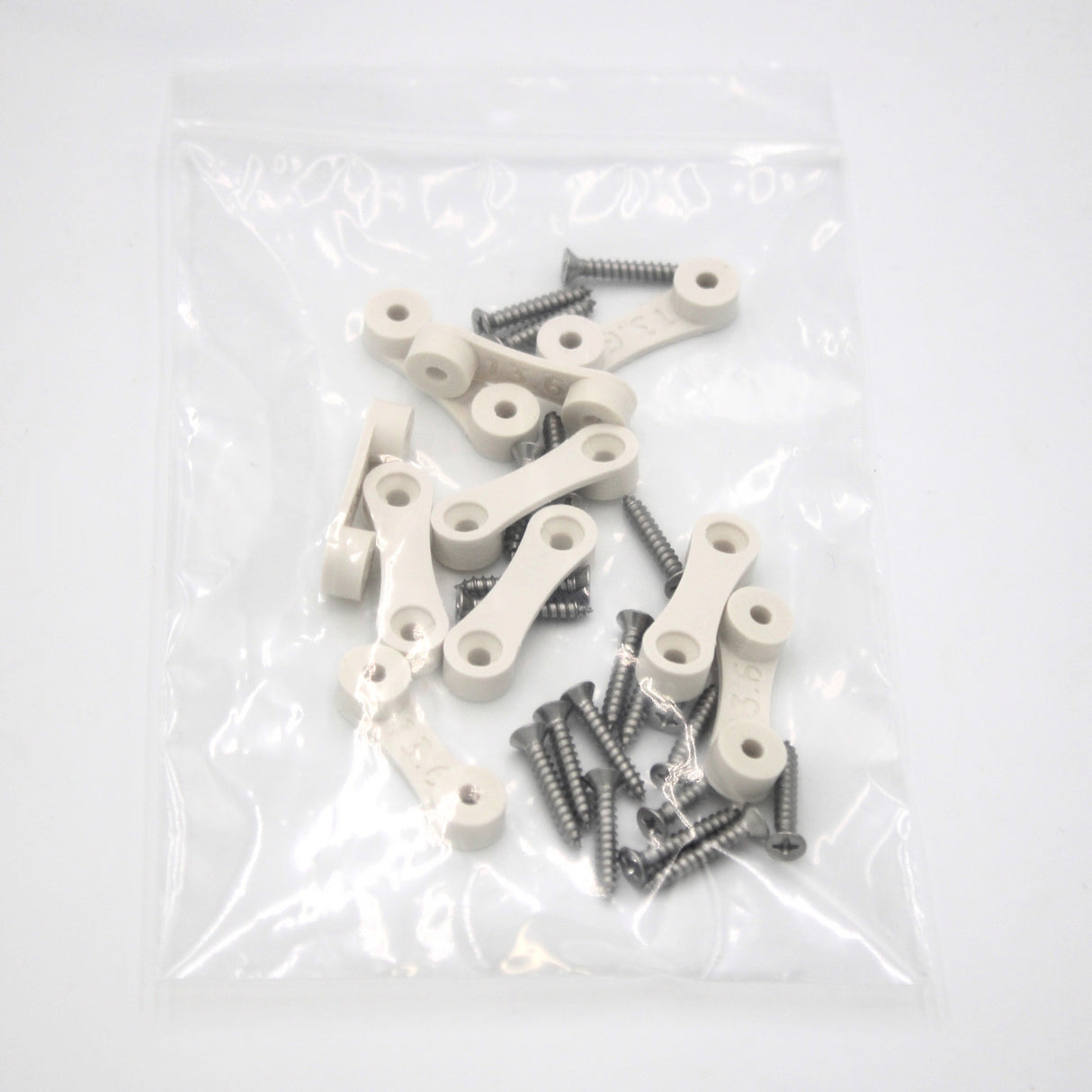 Clear plastic bag containing several LED Strip Saddle white plastic connecting pieces, silver screws, and surface mount accessories on a white background.